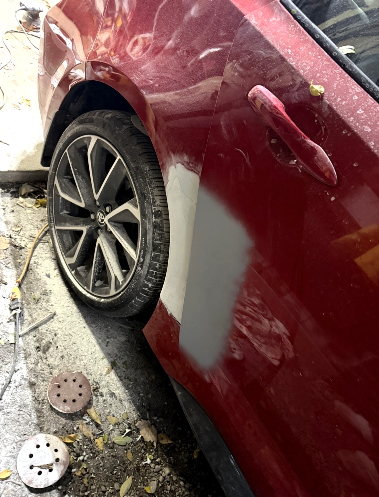 Before paint and body repair on a red Toyota quarter panel
